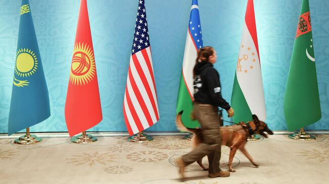 Офицер службы безопасности проходит мимо национальных флагов Казахстана, Кыргызстана, США, Узбекистана, Таджикистана и Туркменистана перед встречей в Ташкенте