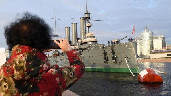 Туристка фотографирует музей Крейсер Аврора в Санкт-Петербурге