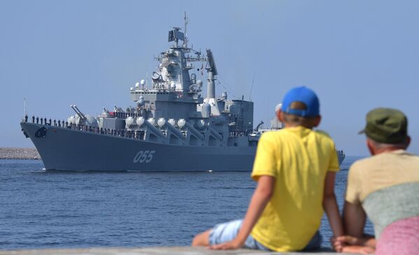 Мужчина с ребенком на набережной наблюдают за подготовкой кораблей ВМФ РФ к параду, посвященному Дню Военно-морского флота РФ, в Кронштадте
