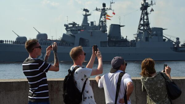 Люди на набережной наблюдают за подготовкой кораблей ВМФ РФ к параду, посвященному Дню Военно-морского флота РФ, в Кронштадте