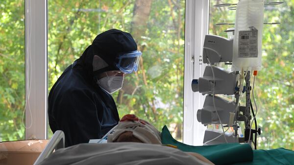 Медицинский работник у постели пациента в отделении реанимации и интенсивной терапии в госпитале COVID-19 в городской клинической больнице № 52 в Москве