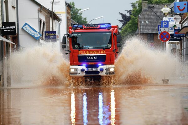 Пожарная машина проезжает по затопленной улице после проливных дождей в Эрфтштадте, Германия