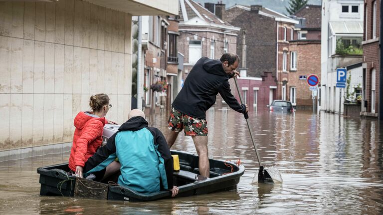 Люди плывут на лодке по жилой улице после наводнения в Англере, провинция Льеж, Бельгия