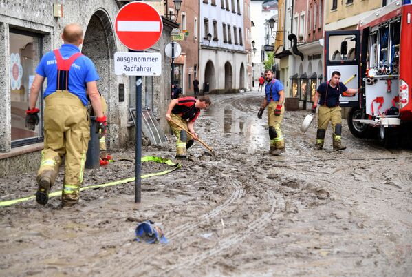 Рабочие очищают улицы от грязи и воды в затопленном историческом центре Халлайна, Австрия