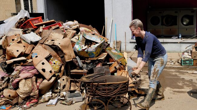 Женщина убирает повреждённые вещи после наводнения в Пепинстере, Бельгия