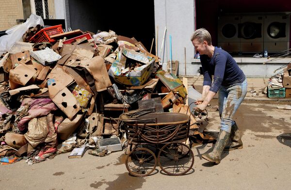 Женщина убирает повреждённые вещи после наводнения в Пепинстере, Бельгия