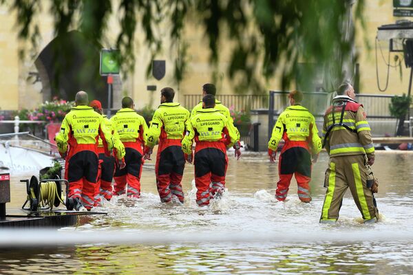 Спасатели идут по затопленной улице после проливных дождей в Валкенбурге, Нидерланды