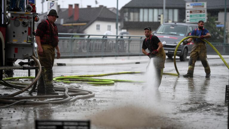 Люди убирают грязь после наводнения в центре города Халлайн, Австрия