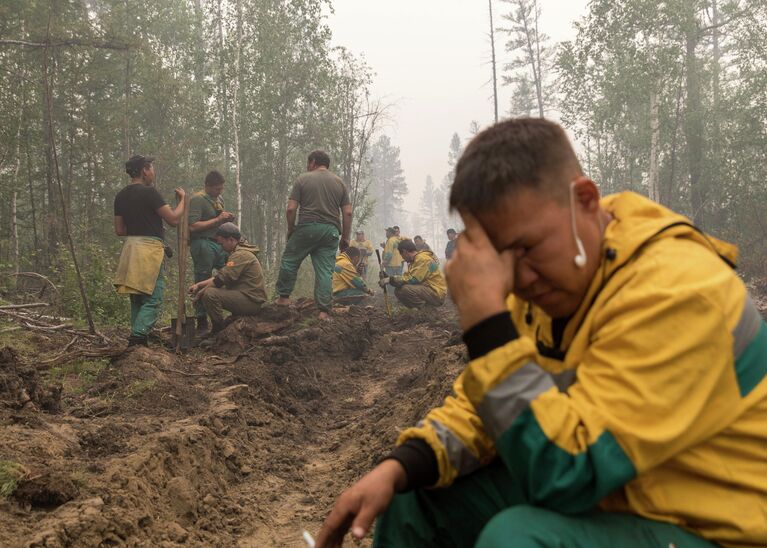 Люди копают траншеи во время тушения лесных пожаров в Якутии