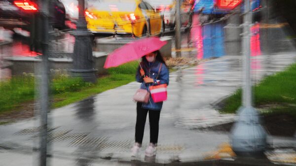 Девушка под зонтом у пешеходного перехода во время дождя