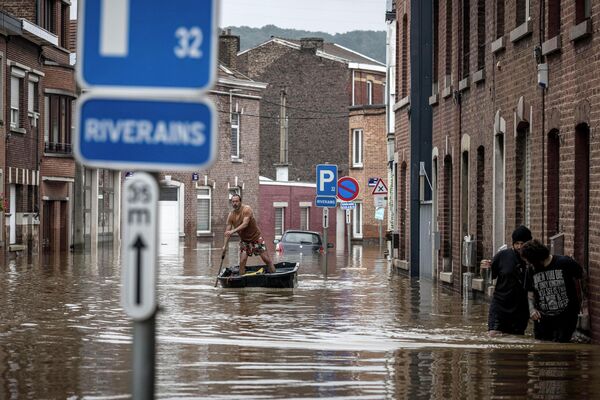 Мужчина плывет на лодке по жилой улице после наводнения в Англере, Бельгия