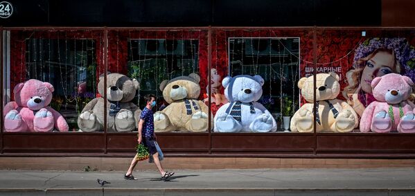 Молодой человек проходит мимо витрины с мягкими медведями в Москве 
