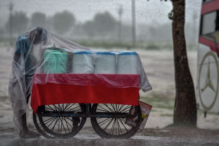 Уличный торговец укрывается от дождя в Аллахабаде 