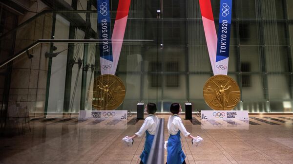 A woman walks near a large-scale reproduction of the Tokyo 2020 Olympic Games gold medal as part of the Olympic Agora event at Mitsui Tower in Tokyo on July 14, 2021. (Photo by Philip FONG / AFP)