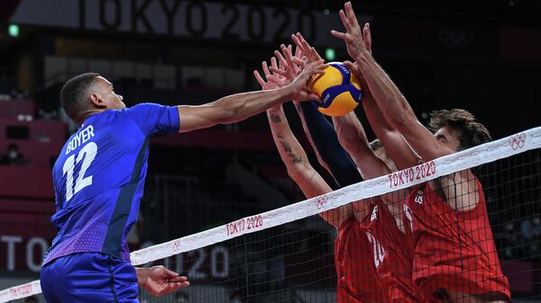 (R-L) USA's Torey Defalco and David Smith block a shot by France's Stephen Boyer in the men's preliminary round pool B volleyball match between USA and France during the Tokyo 2020 Olympic Games at Ariake Arena in Tokyo on July 24, 2021. (Photo by Yuri Cortez / AFP)