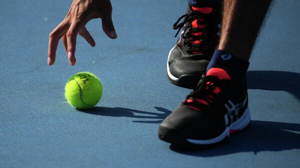Волонтер подает теннисный мяч на Олимпиаде в Токио