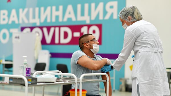 Посетитель делает прививку в центре вакцинации от COVID-19 в Гостином дворе в Москве