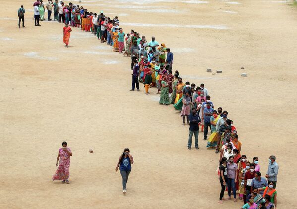 Сотни людей выстраиваются в очередь, чтобы получить вторую дозу вакцины против коронавируса на муниципальной территории в Хайдарабаде, Индия.