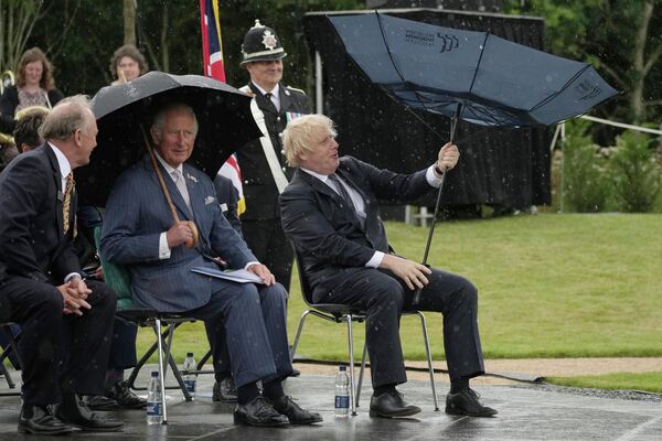 Британский принц Чарльз и премьер-министр Борис Джонсон укрываются от дождя во время открытия Мемориала полиции Великобритании в Национальном мемориальном дендрарии в Олревасе, Англия