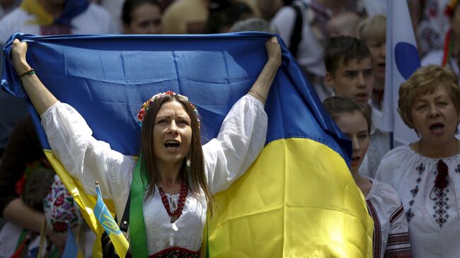 Женщина в вышиванке с украинским флагом на марше в Киеве, Украина