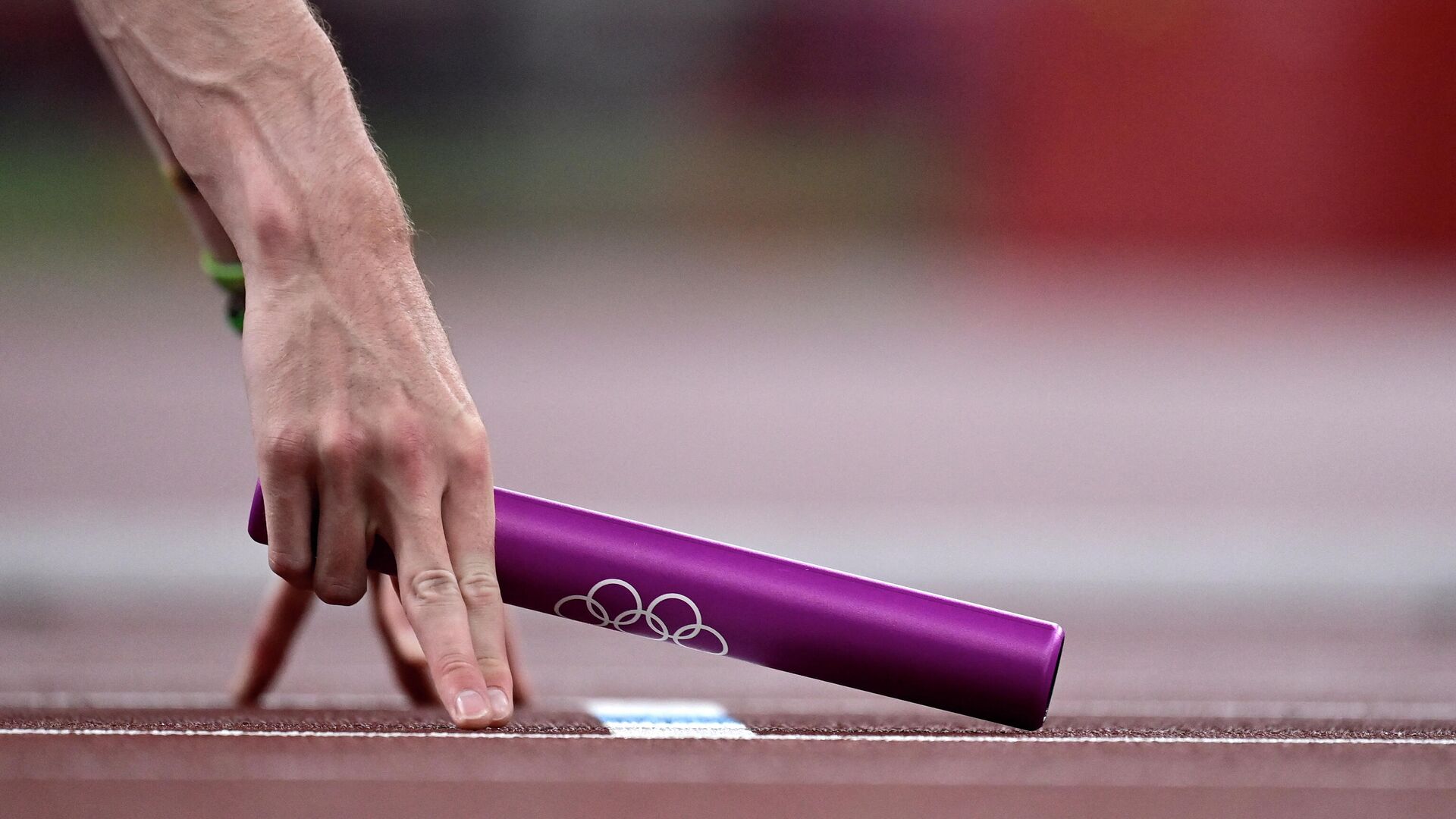 An athlete holds a relay baton ahead of the mixed 4x400m relay heats during the Tokyo 2020 Olympic Games at the Olympic Stadium in Tokyo on July 30, 2021. (Photo by Javier SORIANO / AFP) - РИА Новости, 1920, 30.07.2021