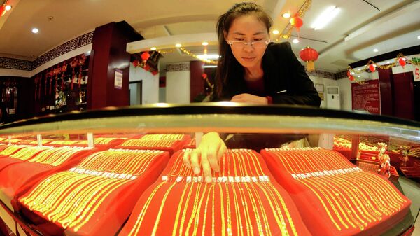Продавец китайских ювелирных изделий демонстрирует золотые ожерелья для продажи в магазине в Циндао, китайская провинция Шаньдун.
