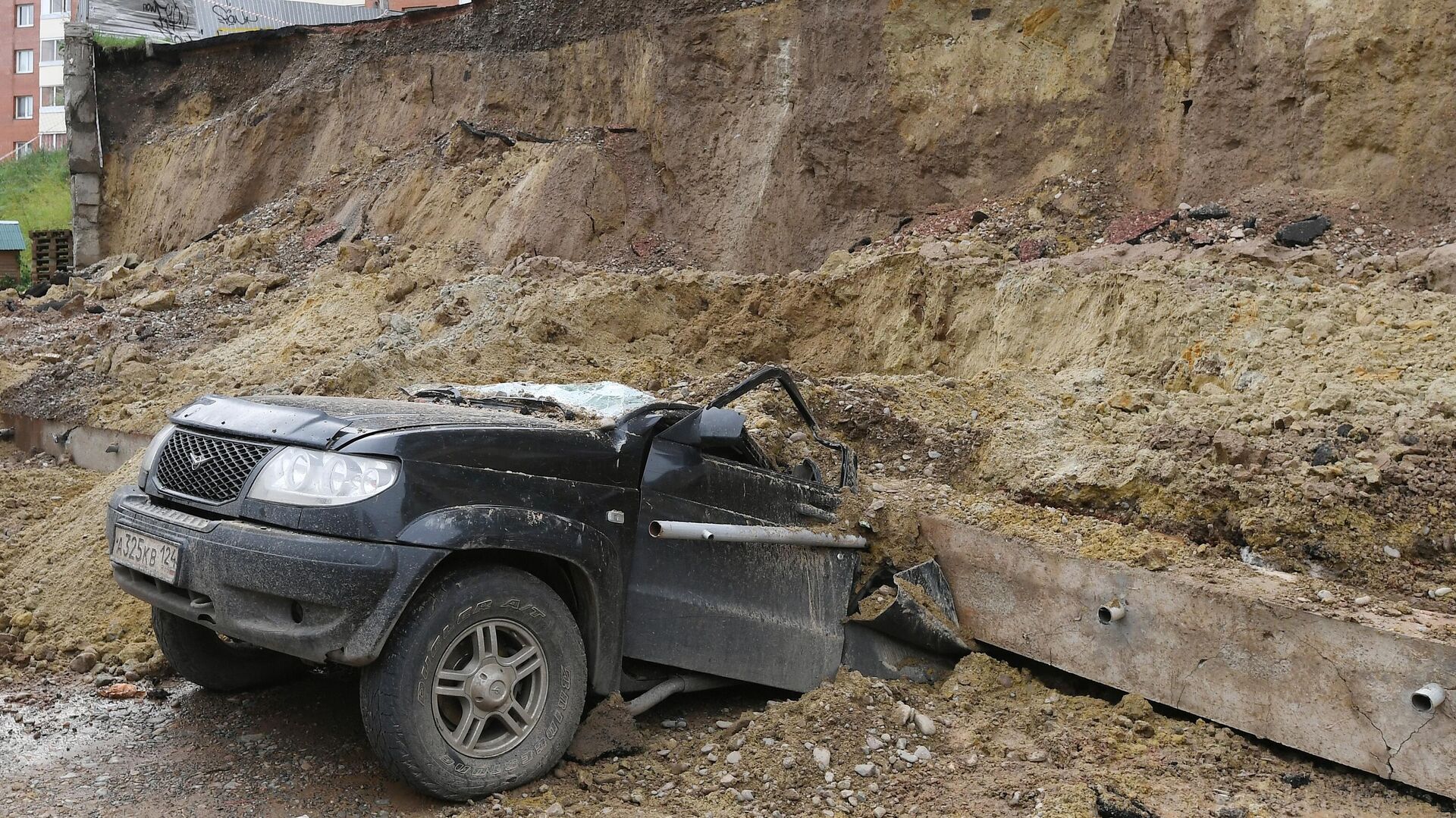 Легковой автомобиль, раздавленный обрушившейся подпорной стеной, возле жилого дома в Красноярске - РИА Новости, 1920, 06.08.2021