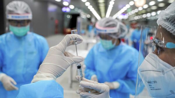 Медицинский работник готовит шприц с дозой вакцины против (COVID-19)