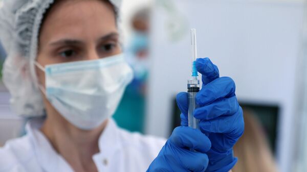 Медицинский сотрудник наполняет шприц вакциной от COVID-19