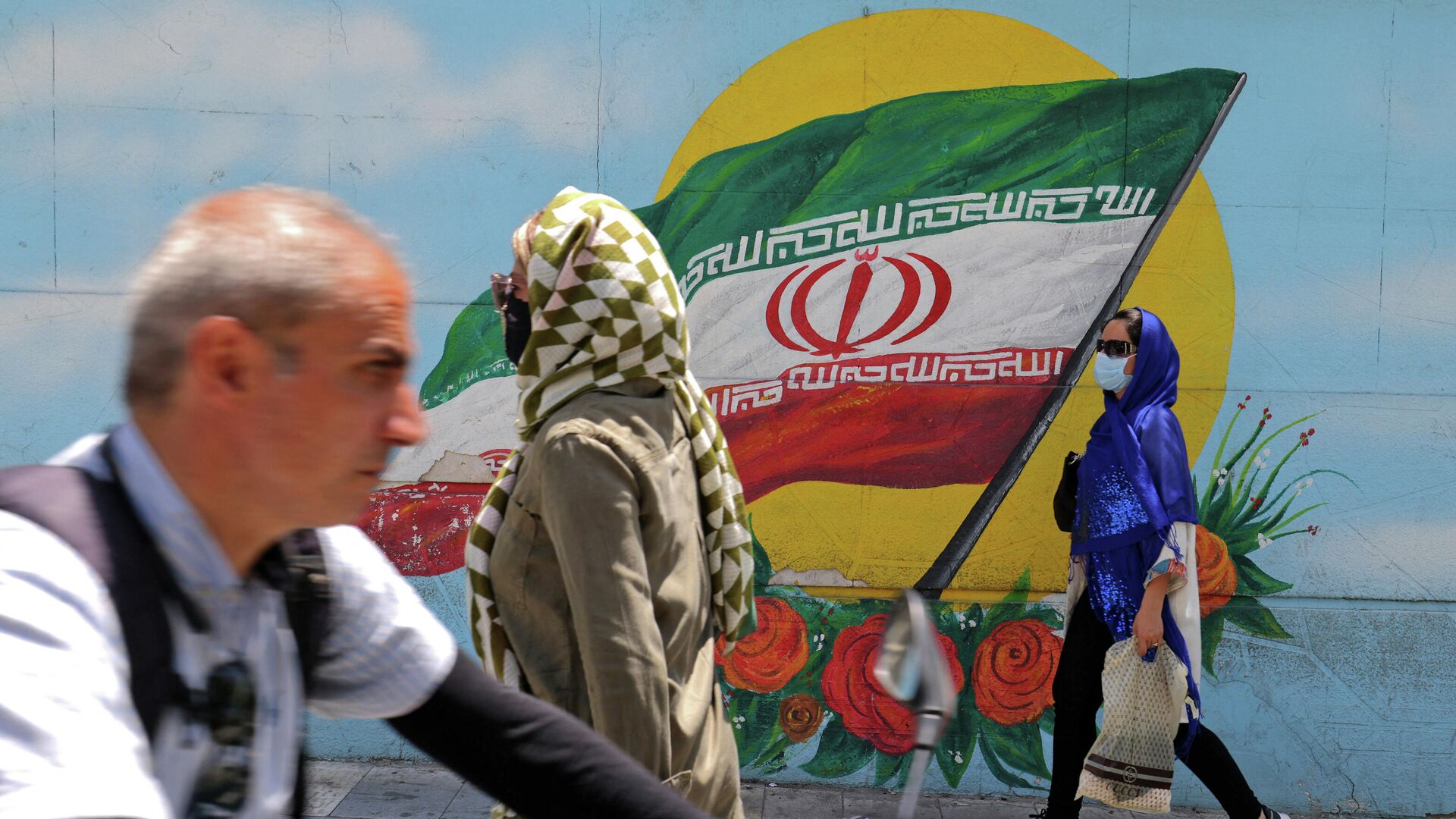 Иранцы в масках проходят мимо фрески с изображением национального флага Ирана в Тегеране  - РИА Новости, 1920, 12.08.2021