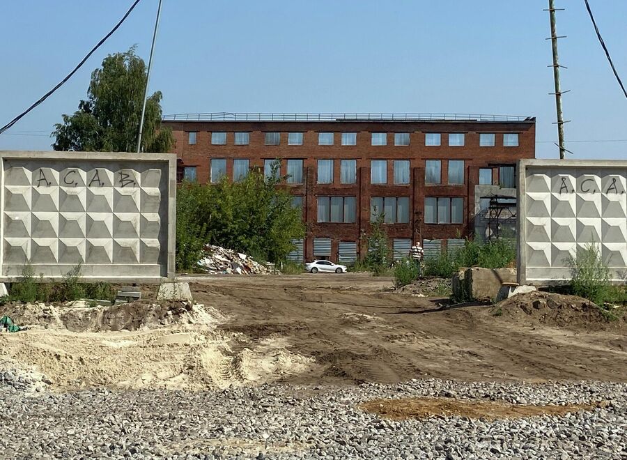 Территория бывшего завода ограждена бетонным забором