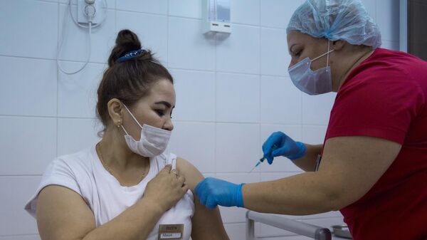 Медицинский сотрудник делает женщине прививку от COVID-19 в Санкт-Петербурге