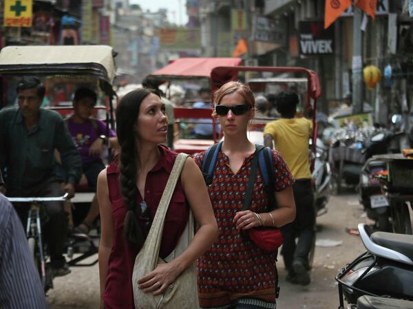 Туристы идут по улице возле железнодорожного вокзала в Нью-Дели, Индия