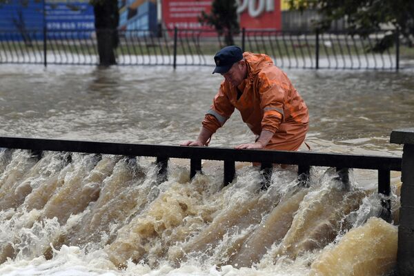 Сотрудник коммунальной службы на подтопленной в результате ливневых дождей улице в Керчи