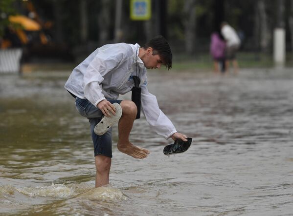 Молодой человек на подтопленной в результате ливневых дождей улице в Керчи