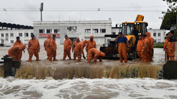 Сотрудники коммунальной службы на подтопленной в результате ливневых дождей улице в Керчи