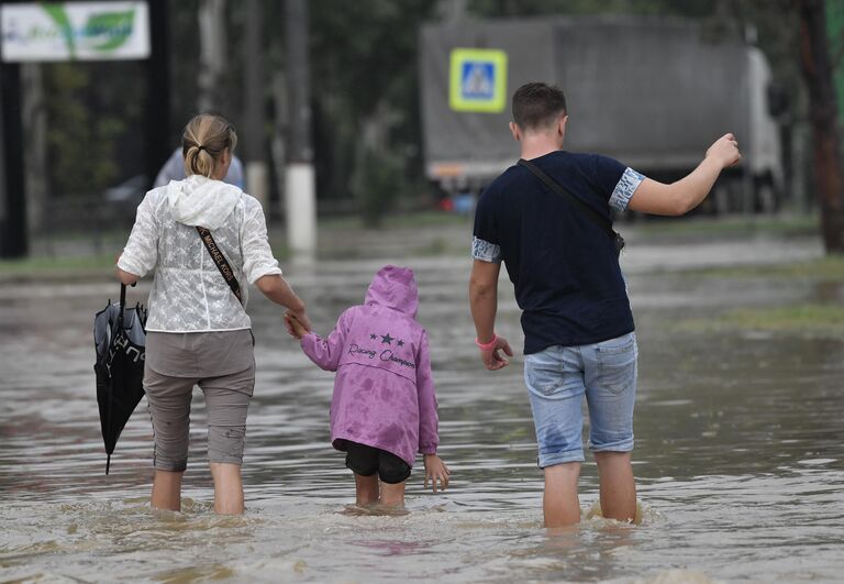 Прохожие на подтопленной в результате ливневых дождей улице в Керчи