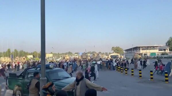 Толпа людей бежит к терминалу аэропорта Кабула после того, как боевики Талибана*  взяли под контроль президентский дворец