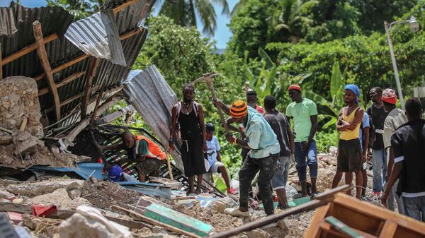 Местные жители ищут жертв в доме, разрушенном землетрясением, Гаити