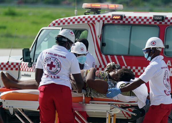 Работники скорой помощи увозят пострадавшего от землетрясения, Гаити