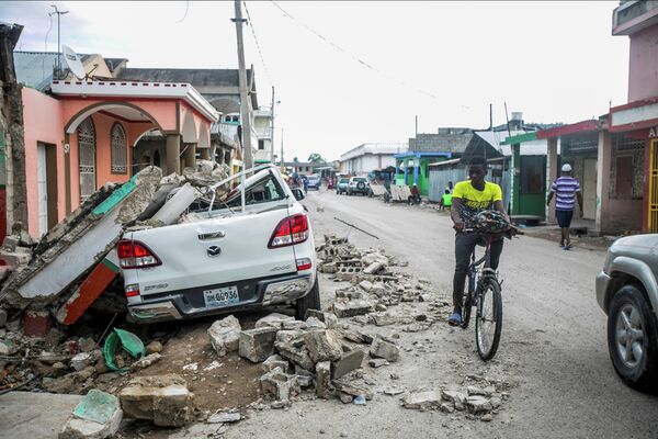 Поврежденный автомобиль под обломками после землетрясения в Гаити