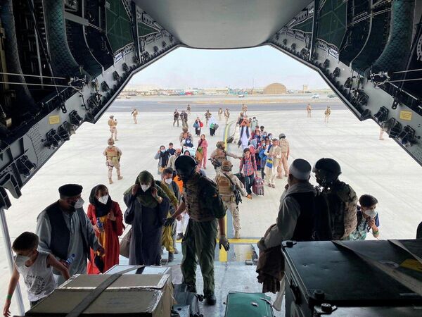 Граждане Испании, проживающие в Афганистане, и афганцы садятся в военный самолет в международном аэропорту в Кабуле, Афганистан