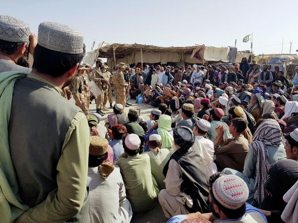 Солдаты пакистанской армии разговаривают с людьми, которые собираются пересечь пункт пропуска в пакистано-афганском пограничном городе Чаман
