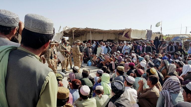Солдаты пакистанской армии разговаривают с людьми, которые собираются пересечь пункт пропуска в пакистано-афганском пограничном городе Чаман