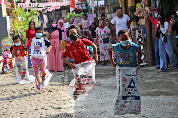 Дети принимают участие в соревнованиях по прыжкам в мешках во время празднования Дня независимости в Джакарте, Индонезия