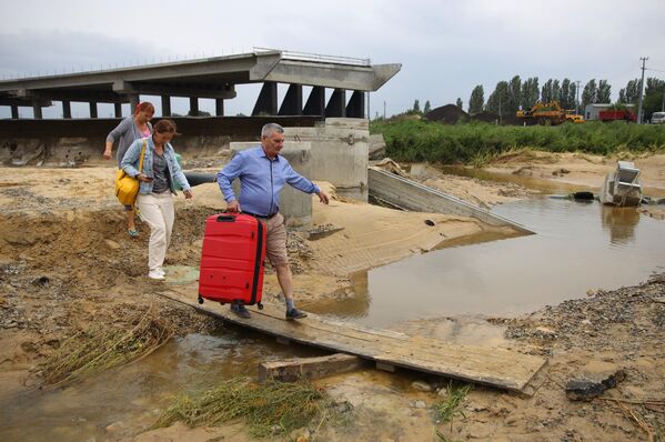 Люди пытаются пешком добраться до аэропорта по размытой ливнями дороге А290 в районе села Цибанобалка в Краснодарском крае