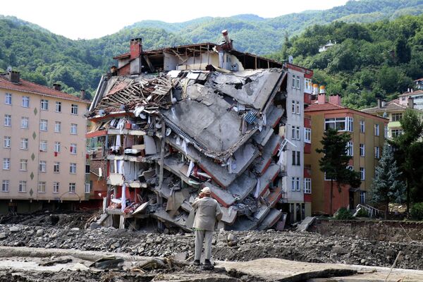 Мужчина смотрит на разрушенное здание в результате наводнения, Турция