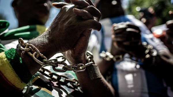 Члены Форума африканской диаспоры (ADF) с цепями на руках в знак демонстрации протеста против работорговли и торговли людьми