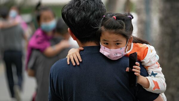Отец несет своего ребенка в детский сад в Пекине 