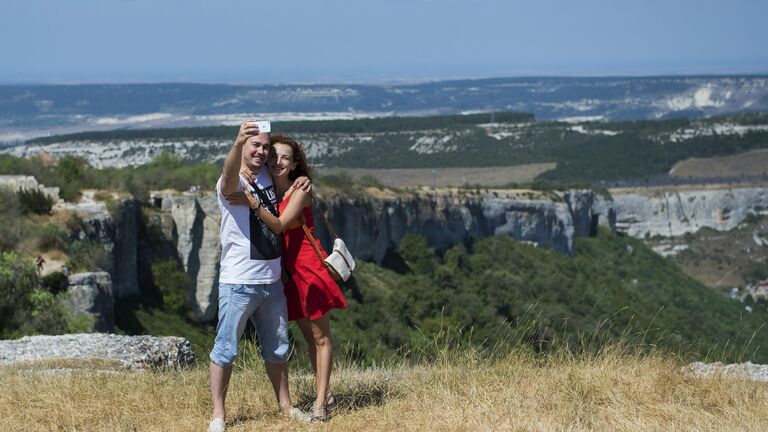 Мужчина и женщина делают селфи на верхнем плато пещерного города Чуфут-Кале в Крыму